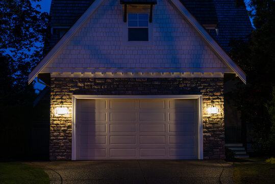 Garage door in luxury house with trees and nice landscape in Spring in Vancouver, Canada, North America. Night time on April 2025.