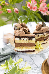 Close up cake with white and chocolate sponge cake, milk ganache based on cream and chocolate ganache based on cream cheese. in the background a vase with alstroemerias