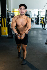 Young bodybuilder doing cable crossover exercise in gym
