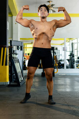Young bodybuilder showing his muscles in a gym