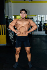 Young bodybuilder showing muscles in the gym