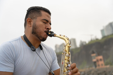 Young musician playing saxophone on beach seeking inspiration