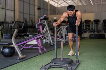 Fototapeta premium Fitness Training. Man pushing sled in gym for strength and conditioning workout.