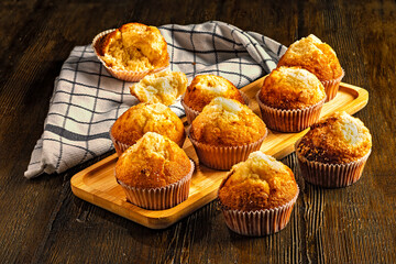 Fresh muffins on wooden tray with kitchen cloth