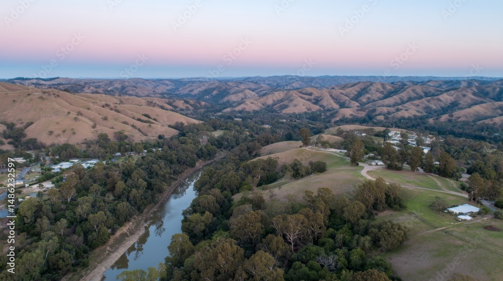 Aufkleber A gentle stream winds through serene green hills under the soft glow of dawn, creating a peaceful landscape that radiates tranquility and connection to nature