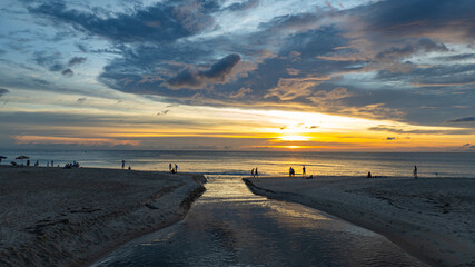 The water from the canal flows to meet with the sea water..Golden sparkles in the sky shine in the...