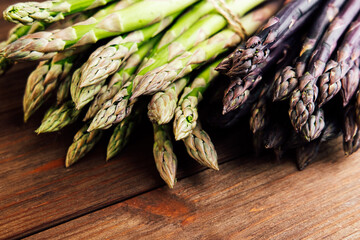 Fresh asparagus varieties displayed on wooden table in a rustic kitchen setting