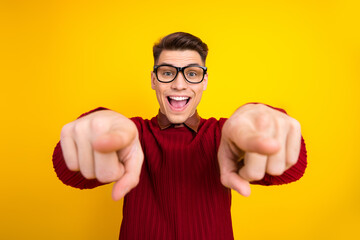 Happy Young Man in Glasses Pointing and Smiling on Yellow Background