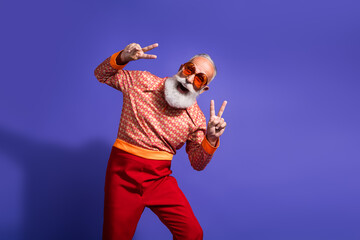 Stylish mature man in retro outfit posing with energetic hand gestures on a vibrant violet background