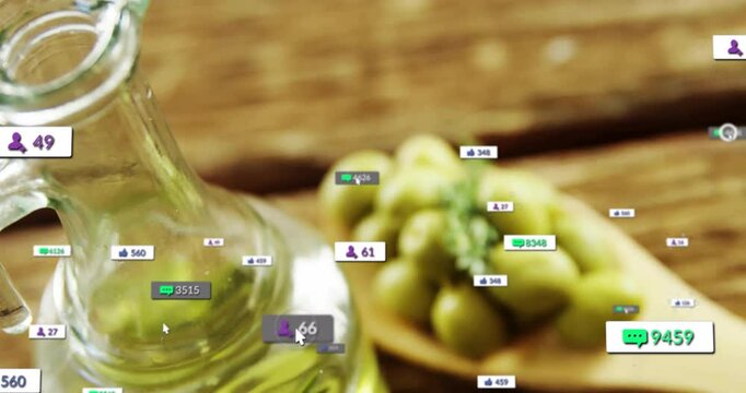 Glass olive oil bottle standing beside wooden spoon holding olives and social media icons floating