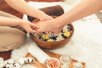 Woman indulges in blissful foot massage at luxurious spa salon while masseur give reflexology therapy in gentle day light ambiance resort or hotel foot spa. Quiescent
