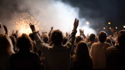 Large crowd jumps and dances with excitement as colorful pyrotechnics illuminate the night sky during a dynamic concert filled with vibrant energy