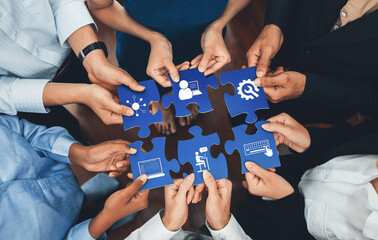Diverse hands holding puzzle pieces symbolize teamwork and collaboration in a modern office, highlighting business solutions and digital connectivity for innovative progress. Amity