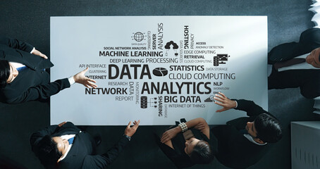 A group of business professionals engaging in a strategic discussion centered around data analytics, exemplified by a visual concept on a table showcasing various technology elements. Amity