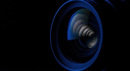 Camera lens with blue reflection on black background close up view.