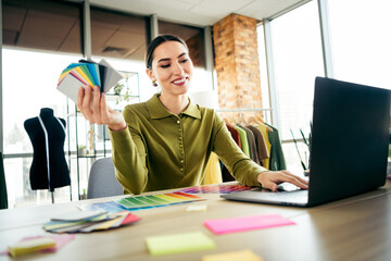 Professional fashion designer working with fabric samples in a modern atelier office with a stylish...