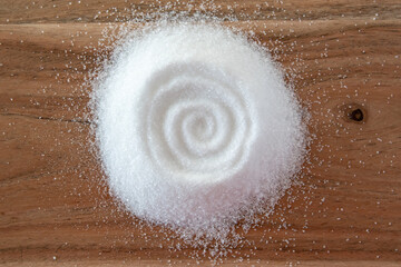 Granulated sugar on the natural wooden background.