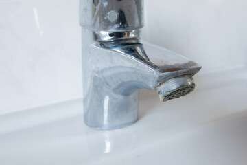 Metal tap with much water  limescale water in bathroom.