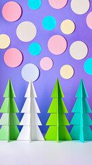 Cute DIY style trendy Nordic Noel folded paper Christmas tree decorations mobile backgrounds in bright turquoise green pink and purple with cut out polka-dots