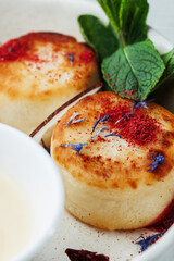 macro dessert on white plate with mint leaves. Elegant breakfast with cottage cheese pancakes, berry sauce, and cream