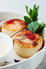 cheese pancakes on white plate with mint leaves. Elegant breakfast with cottage cheese pancakes, berry sauce