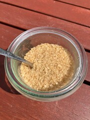 Brauner Zucker in einem Glas mit Löffel