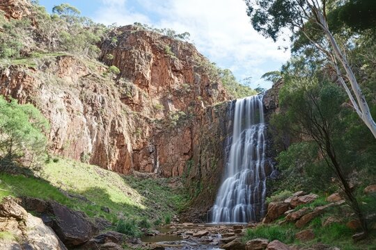 Majestic waterfall cascades from rocky cliffs in Morialta Conservation Park during daytime, High waterfall falls from cliff in Morialta conservation park and nature reserve