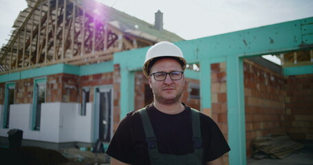 Construction worker in hard hat with serious expression at building site, focused on construction project, experienced professional in industry, dedicated to quality work