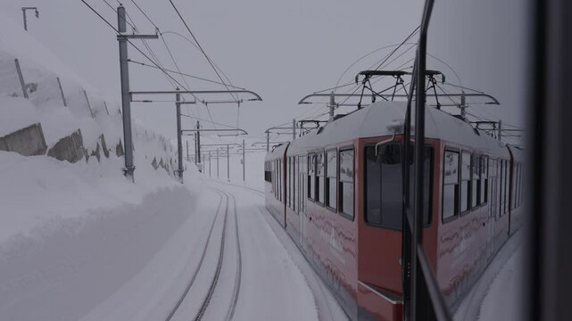Slow Motion Shot Of Red Gornergrat Train Moving On Tracks Amidst Snow Against Sky During Winter - Zermatt, Switzerland