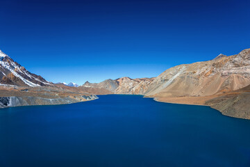 Still blue lake under the clear blue sky. Tilicho lake in calm weather in autumn sunny day. A sacred lake in Himalaya mountains near Manang, Nepal.