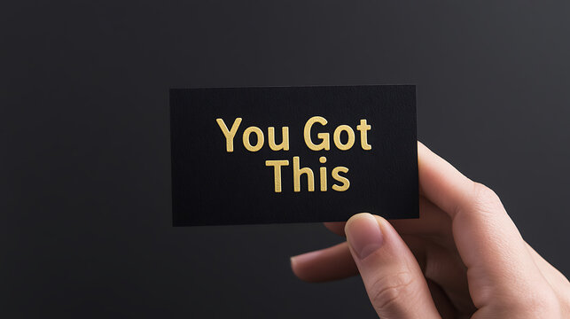 Inspirational message: A hand holds a card with the motivational quote "You Got This", symbolizing encouragement and self-belief against a plain background. - Powered by Adobe