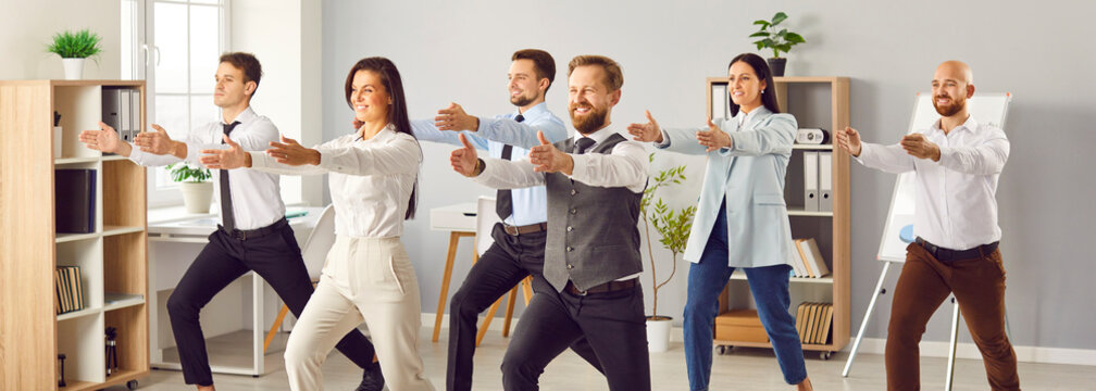 A group of young business people in the office doing exercises together. A successful team stretches during the break. Concept employee engagement, building activity, employees together