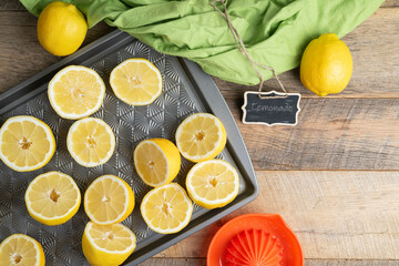 Lemons cut in halves on a baking sheet, preparing to make lemonade.