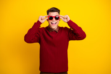 Handsome Happy Young Man Posing with Red Sunglasses Against Vibrant Yellow Background