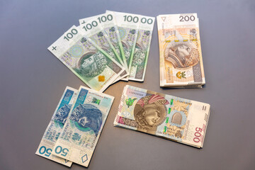 Banknoty, złotówki, pieniądze leżące na szarym tle