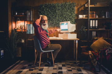 Fototapeta premium Elderly man using a vintage computer at home office, surrounded by books and learning materials, symbolizing technology and remote working
