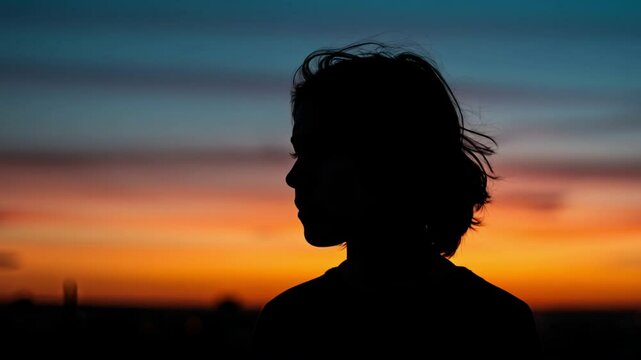 Human silhouette against a vivid sunset sky, with soft light outlining the figure