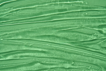 Vibrant green cosmetics skincare gel with fluid streaks and tiny air bubbles, showing a glossy,...