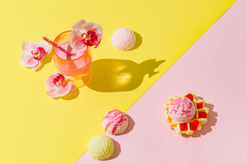 Summer scene with pink tropical drink, orchid flowers, waffle and ice cream scoops on pastel pink and yellow background. Sun and shadows. Cocktail aesthetic concept. Trendy summer party idea.