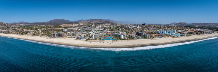 wide angle, panoramic aerial landscape view of Hotel Zone with white sand beach (Playa Hotelera) in San José del Cabo B.C.S., Mexico with many hotel close to beach and mountain landscape in background