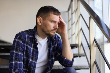 Depressed man sitting on stairs in building