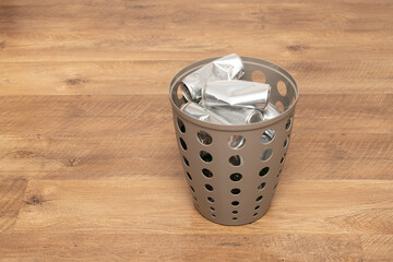Aluminum waste is being sorted in a recyclable container placed on a wooden surface, emphasizing...