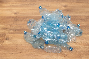 A collection of used plastic water bottles is piled together on a wooden surface, highlighting the...
