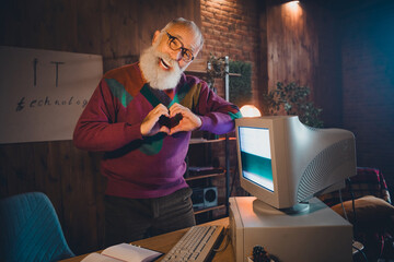 Elderly man working with a computer in a cozy office setting, showcasing programming and...