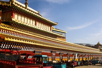 Colorful facade of Kirti Monastery (Gerdeng) in Ngawa, Amdo, Tibet, showcasing traditional Tibetan architecture and rows of vibrant prayer wheels lined along the outer wall.