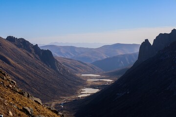Mountain valley landscape in Amdo region featuring winding rivers and rugged peaks, showcasing the natural beauty of Qinghai on the Tibetan Plateau.

