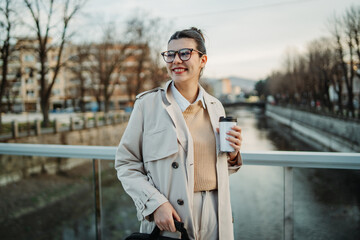 Obraz premium Young caucasian woman walk home from work drink coffee and use cellphone 