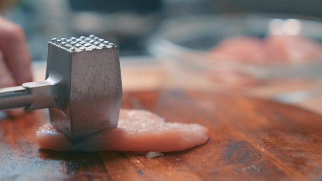 Meat Tenderizer Hammer Pounding Turkey Fillet on Wooden Cutting Board in Slow Motion