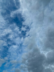 Stormy sky with dark, snowy clouds on a spring day. Clouds are floating across the sky. Dramatic clouds. Dark blue clouds swiftly floating across blue sky. Sky texture, abstract nature background.