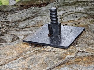 Plate and anchor bolt. Structural support on natural stone with gap to plate and anchor bolt in rocky base